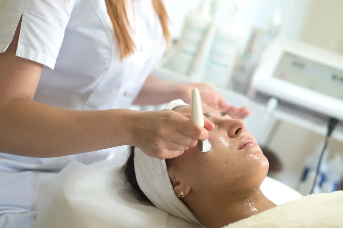 Woman receiving facial cleansing treatment at beauty spa