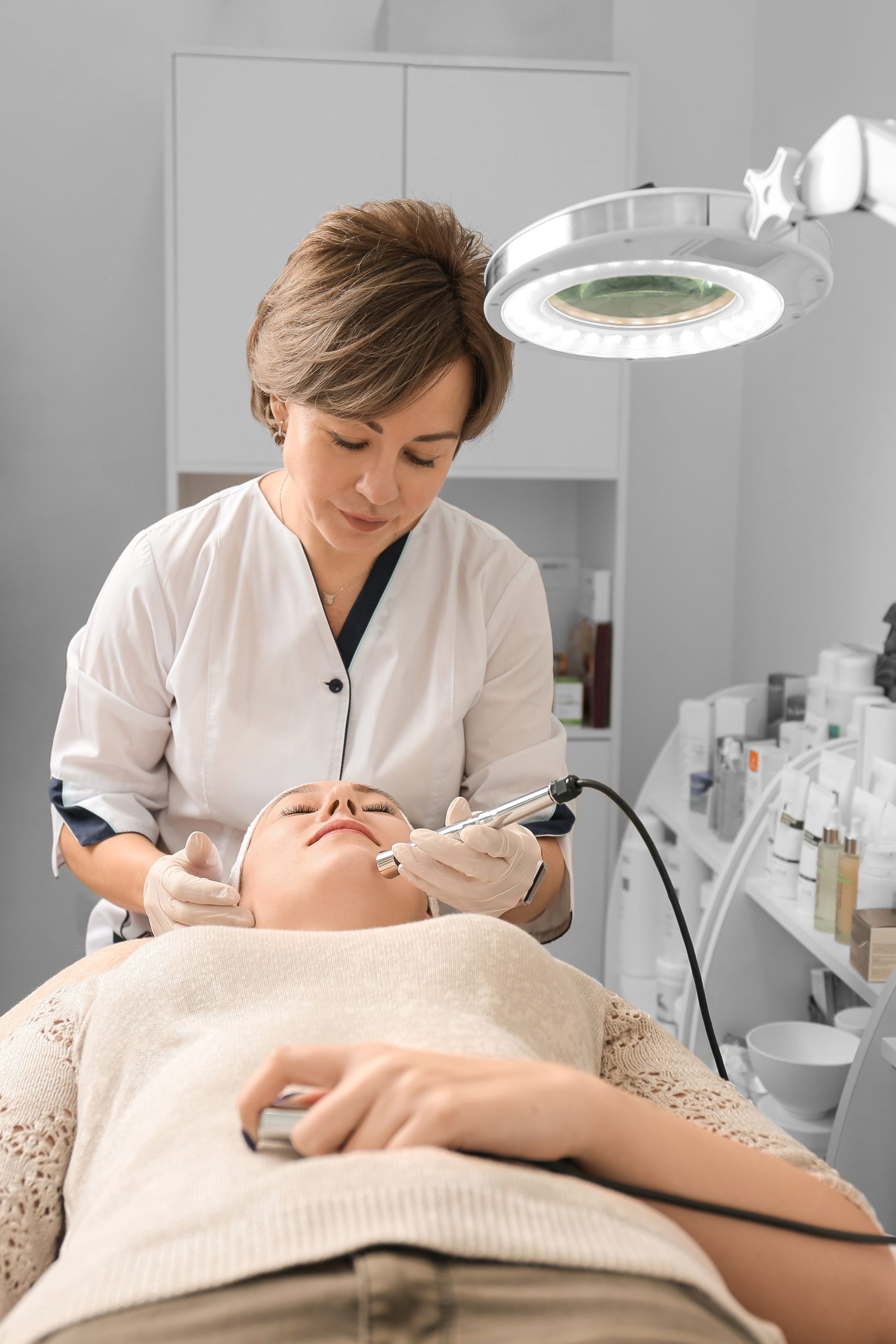 Rejuvenating facial therapy treatment at spa salon clinic. Young beautiful woman getting lifting anti-aging, face massage and skincare by electroporation facial therapy aesthetic cosmetology.