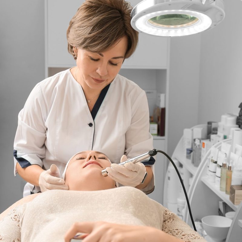 Rejuvenating facial therapy treatment at spa salon clinic. Young beautiful woman getting lifting anti-aging, face massage and skincare by electroporation facial therapy aesthetic cosmetology.